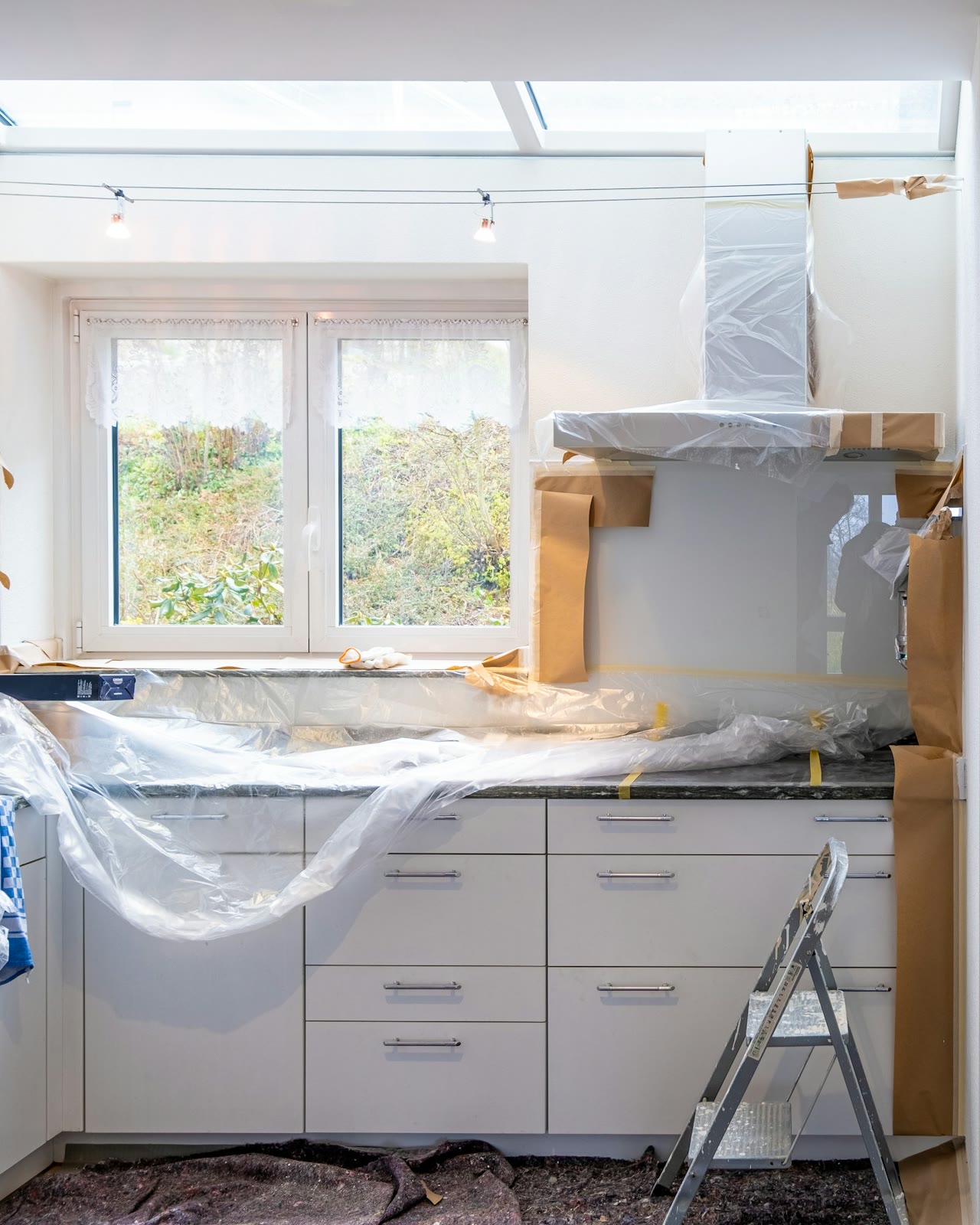A kitchen mid-renovation, cabinets and counters covered in plastic